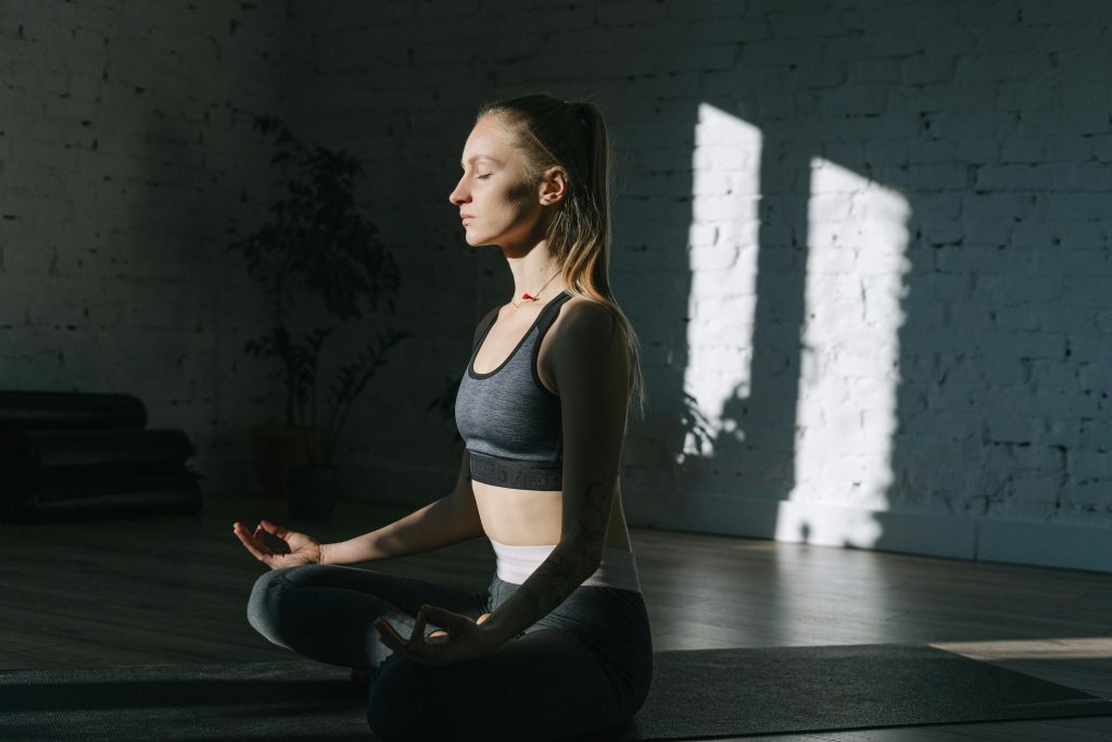 Woman in lotus position meditating indoors, embracing mindfulness and tranquility.